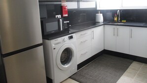 Cocina compacta con refrigerador de acero inoxidable, microondas, lavadora y lavaplatos.