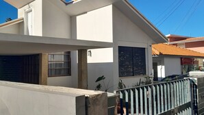 Una casa moderna de dos pisos con techo plano, puerta de garaje visible y entrada protegida por una reja.