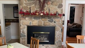 Un salon chaleureux avec une cheminée en pierre, une table à manger en bois et des chaises.