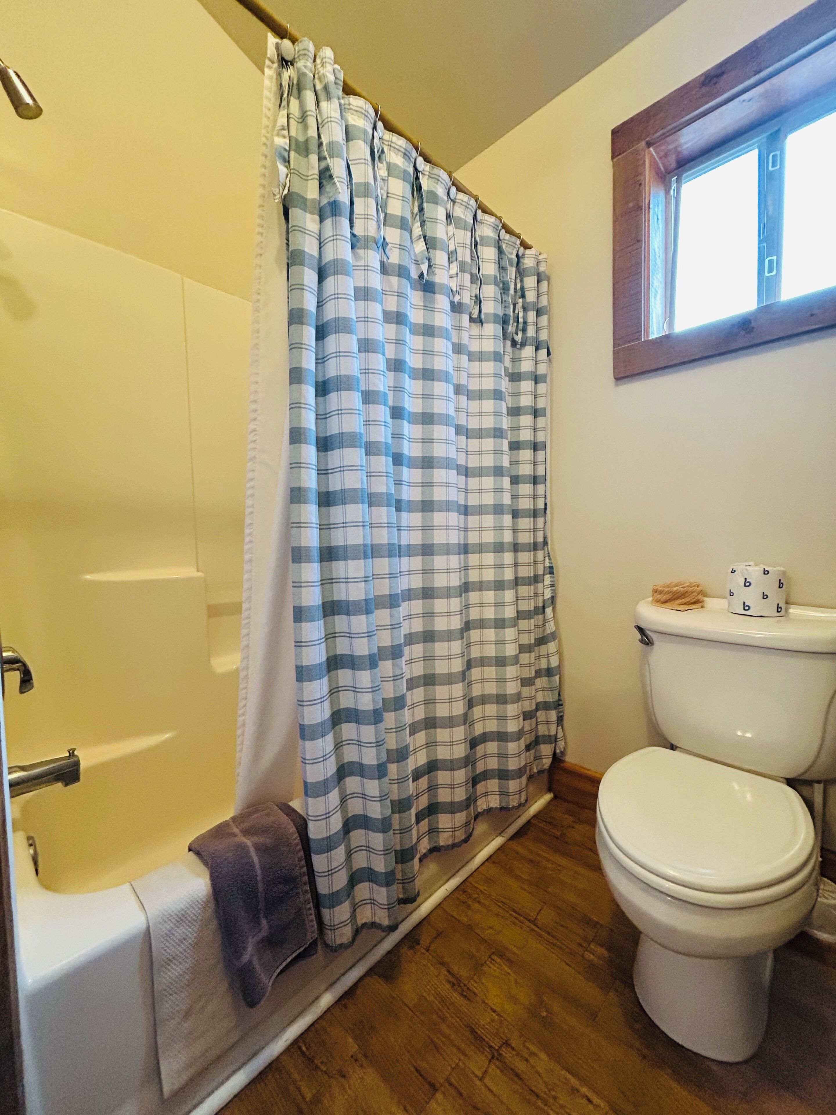 Un baño con bañera, inodoro y cortina de ducha.