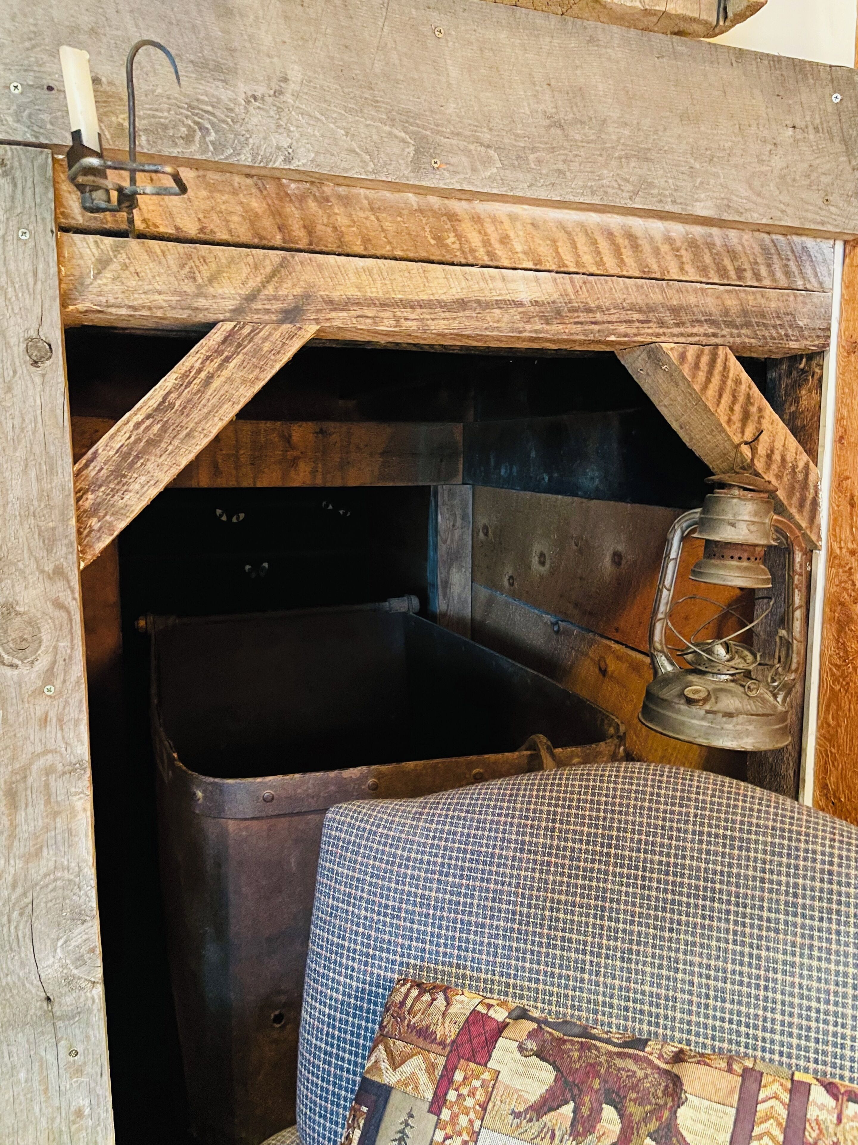 A rustic wooden structure with a metal sink, a lantern, and a patterned cushion.