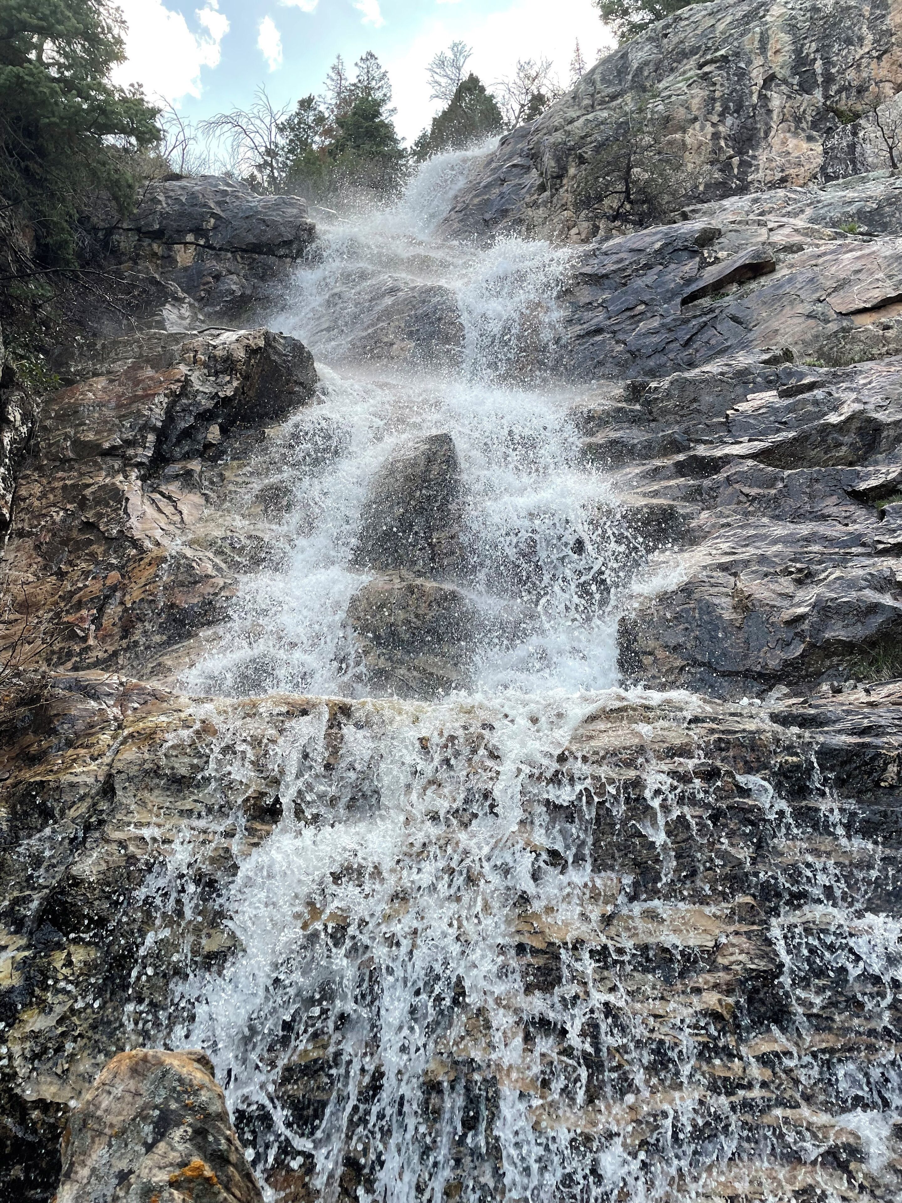 A waterfall cascading over rocky terrain with trees in the background.