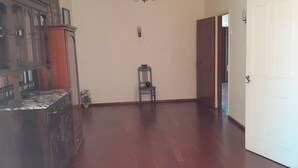Una habitació àmplia amb sòl de fusta, un penjador, un armari de fusta i una porta.