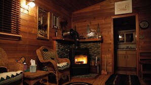 A cozy log cabin interior with a stone fireplace, wicker furniture, and wooden walls. - Welch Cabin - A License to Chill (Kalama)