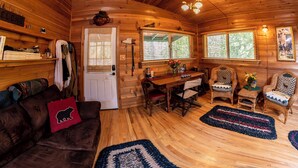 A cozy cabin interior with a wooden interior, a dining area with a table and chairs, and a door with a window. - Welch Cabin - A License to Chill (Kalama)
