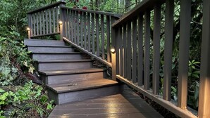 A wooden staircase with railings, surrounded by lush greenery. - Welch Cabin - A License to Chill (Kalama)