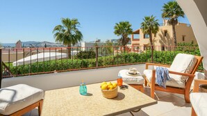 A balcony with a wicker table, a wicker basket of lemons, a drink, and a chair with a towel. - Awesome home in Ibiza (Ibiza)