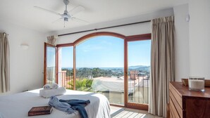A hotel room with a bed, a desk, a glass of milk, and a view of the city and mountains. - Awesome home in Ibiza (Ibiza)