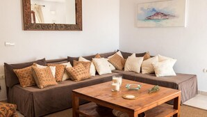 A cozy living room with a brown sectional sofa, patterned cushions, a wooden coffee table with two glasses of milk, a small decorative bowl, and a framed painting on the wall. - Awesome home in Ibiza (Ibiza)