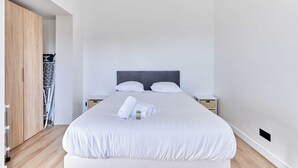 A clean, modern hotel room with a large bed, wooden wardrobe, and a small bedside table. - Appartement Évasion Normande - Welkeys (Cabourg)