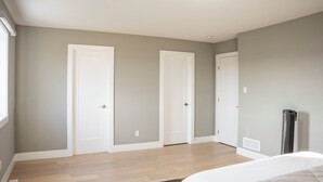 A bedroom with a bed, a heater, and three doors. - Luxury with comfort  (Komoka)