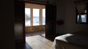 A bedroom with a bed, a window with curtains, and a view of the sea. - Hotel Marshell (Chimo)