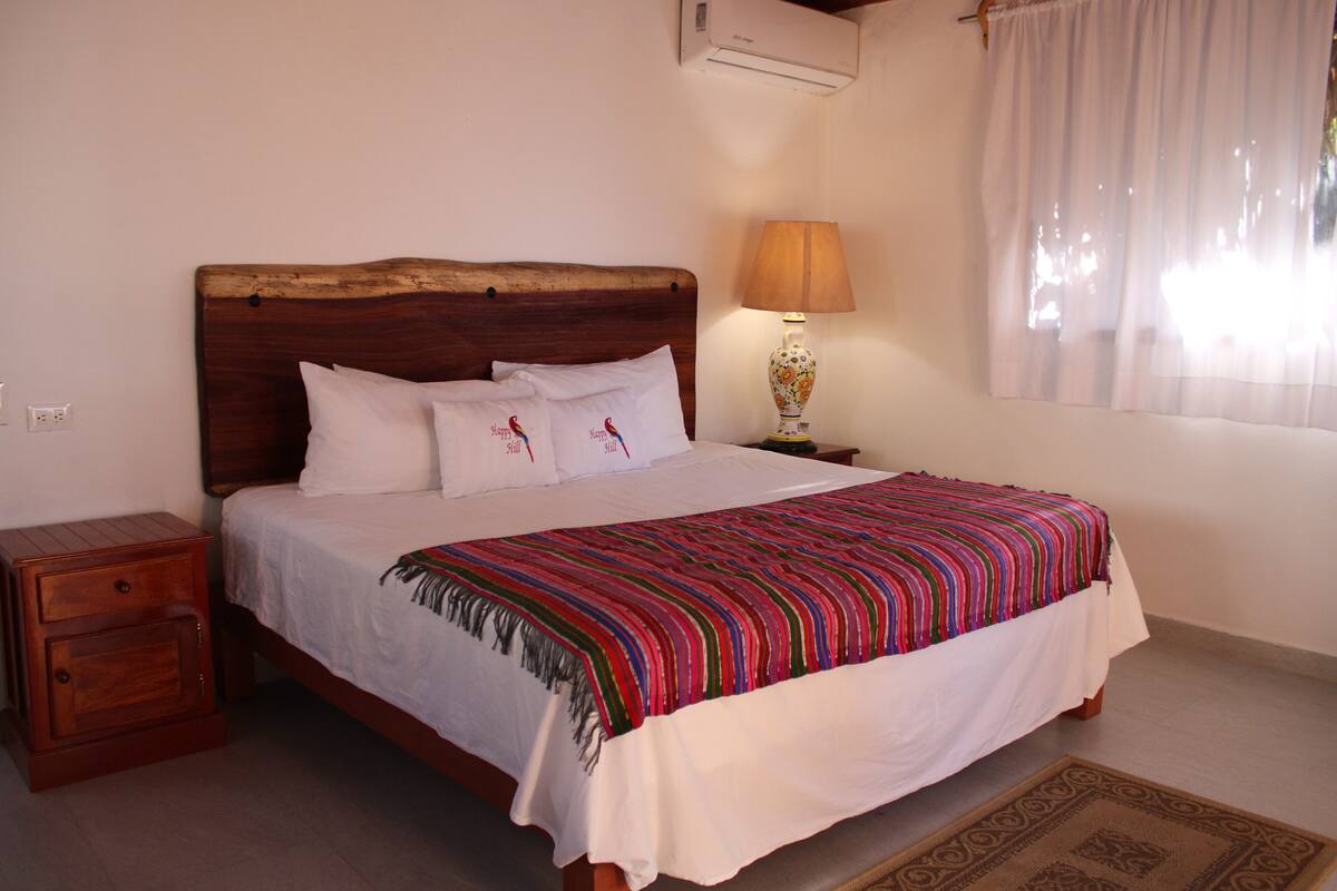 A neatly made bed with a striped blanket, a bedside lamp, and a small wooden nightstand.