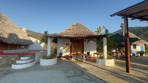 A traditional building with a thatched roof, a covered patio with outdoor seating, and a stone staircase leading to a red platform. - Hotel Marshell (Chimo)