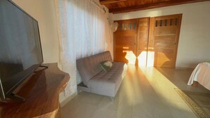 A living room with a sofa, a television on a wooden stand, and a wooden door with a window. - Hotel Marshell (Chimo)