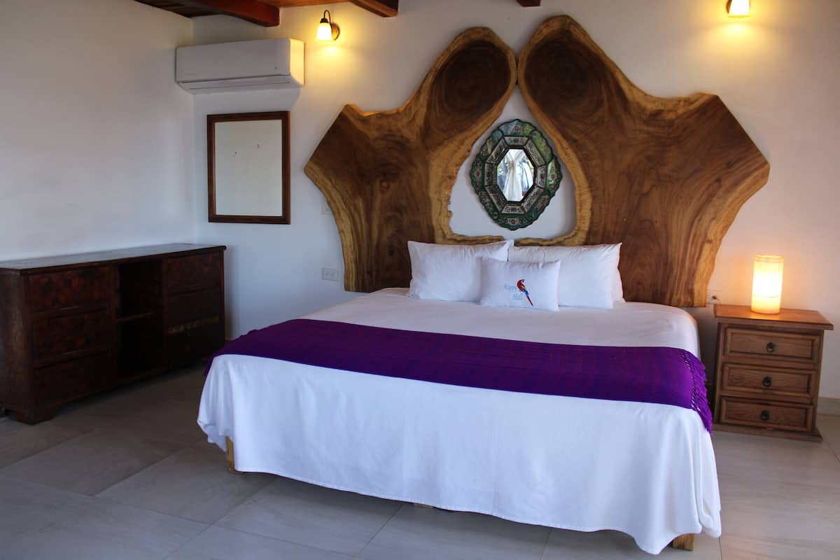 A bedroom with a large bed, a wooden headboard, a nightstand, and a dresser.