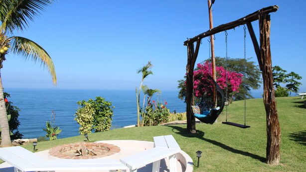 A patio with a swing, a fire pit, and a view of the ocean. - Hotel Marshell (Chimo)