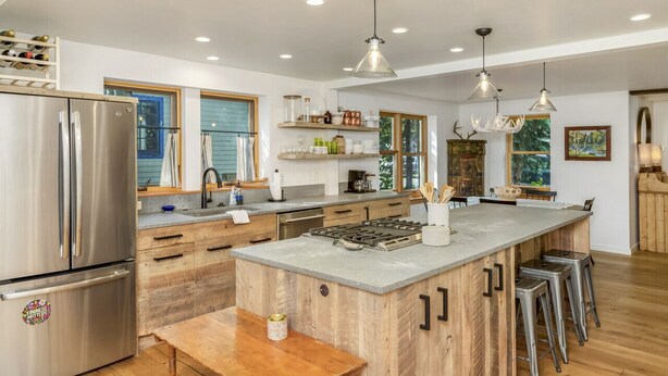 A modern kitchen with stainless steel appliances, wooden cabinetry, and a central island with bar stools. - Lincoln Lodge! Steps from the heart of Elk Avenue! (Crested Butte)