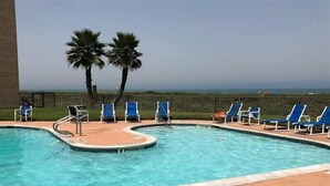 Una piscina amb gandules blaves i palmeres.