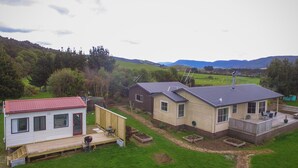 A residential area with houses, a grassy yard, and a hilly landscape in the background.