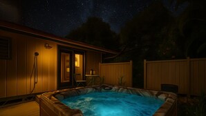 Ein Whirlpool in einem Hinterhof mit Holzzaun, einem Stuhl und einem Tisch.