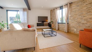 Un salon moderne avec un canapé, une table basse, un téléviseur et un mur en pierre.