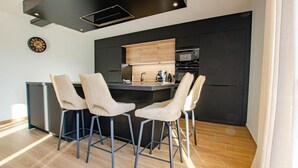 Une cuisine moderne dotée d’un îlot central, de tabourets de bar, d’un four à micro-ondes et d’un four encastré.