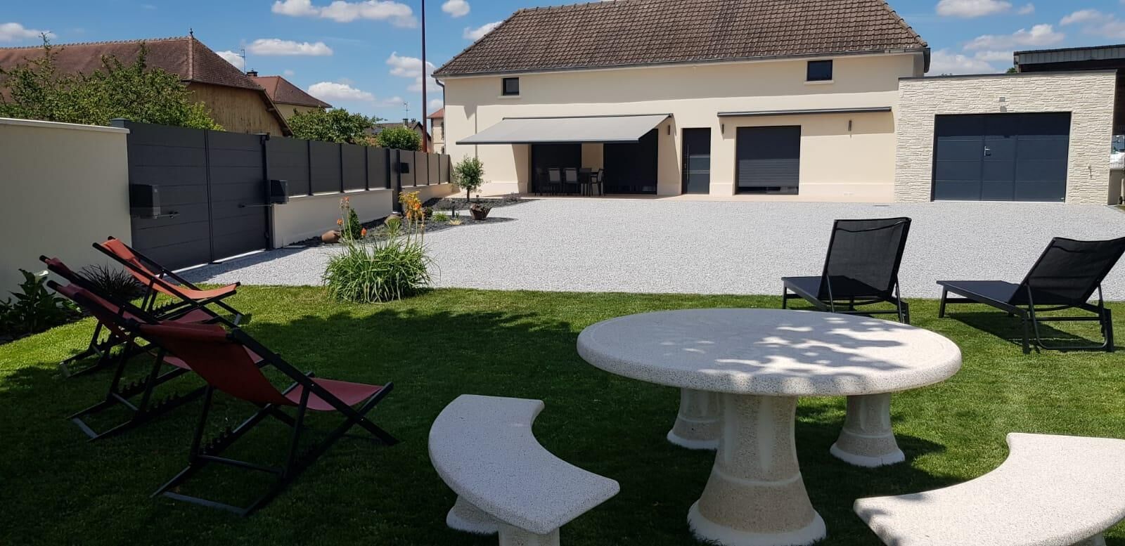 Una casa con patio coperto, posti a sedere all'aperto e vialetto in ghiaia.