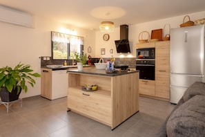 A modern kitchen with a central island, built-in appliances, and a dining area with a sofa. - Holiday Home 'Les Chaudannes' with Mountain View, Wi-Fi, and Air Conditioning (Valgelon-La Rochette)