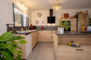 Una cocina moderna con armarios de madera, microondas integrado y un amplio ventanal con cortinas.