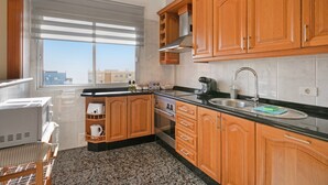 A modern kitchen with wooden cabinets, a stainless steel sink, and a window providing a view of the cityscape.