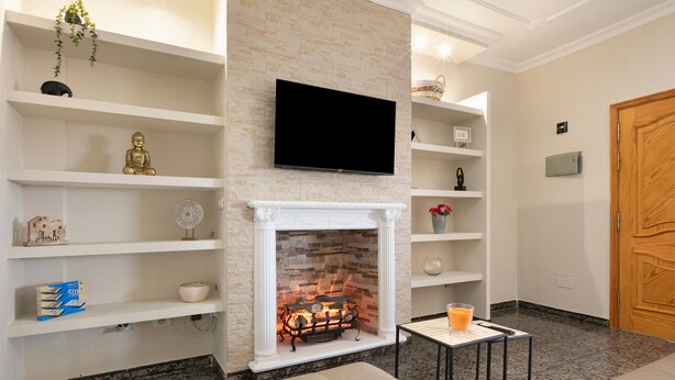 A living room with a fireplace, a television mounted above it, and a sofa.