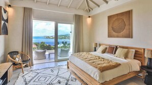 Un dormitorio con una cama grande, vistas al mar y un balcón.