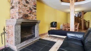 A living room with a fireplace, a black leather sofa, and a yellow wall.