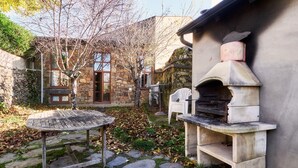 A stone patio with a round table, a stone oven, and a stone wall.