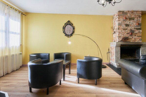 A living room with a fireplace, leather sofas, a coffee table, and a chandelier.