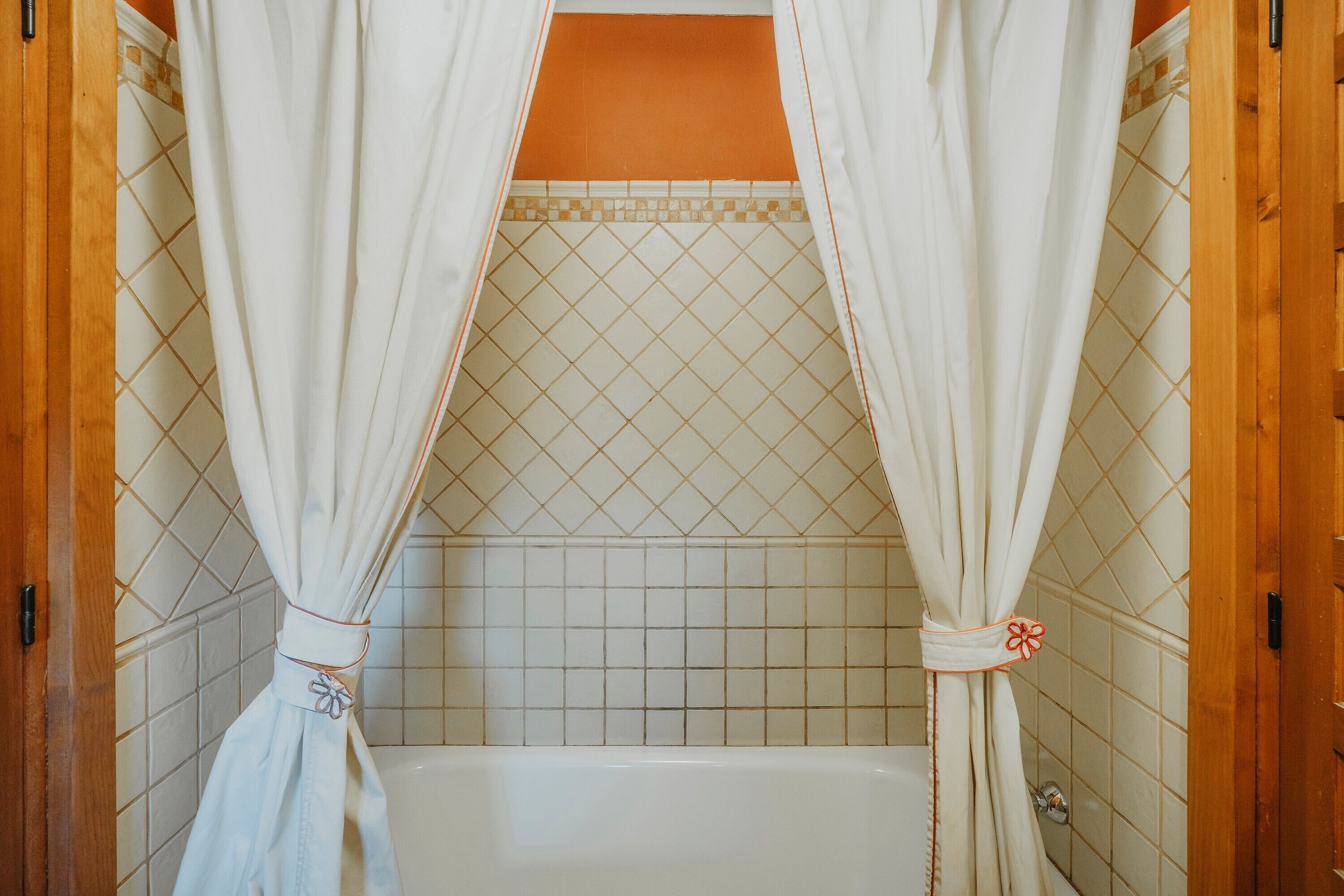 Un baño con bañera, paredes de azulejos y puertas de madera.