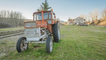 Ein Traktor auf einer Wiese, im Hintergrund ein Haus.