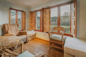 Ein gemütliches Zimmer mit einer Couch, einem Korbsessel und einem Fenster mit Holzhörnern.