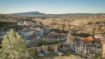 Un pueblo rural con casas de piedra, un cementerio y un paisaje montañoso al fondo.