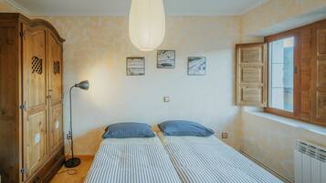 A bedroom with a bed, a wardrobe, a floor lamp, and three framed pictures on the wall.