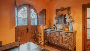 Ein Zimmer mit Holzschrank, Stuhl und einem Fenster mit Rundbogen.