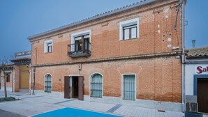 Un edificio in mattoni di due piani con un balcone, finestre ad arco e un cartello con su scritto 'SAB'.