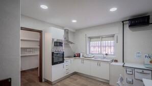 Una cucina moderna con pensili bianchi, forno a microonde, forno e una finestra con persiane.