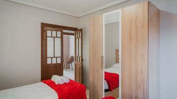Ein Zimmer mit zwei Betten, einem Holzschrank und einer Tür zu einem weiteren Raum.