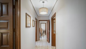 Un corridoio con porte in legno, quadri appesi alle pareti e un pavimento decorato.