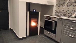 Eine Küche mit eingebautem Holzofen, einer Mikrowelle und einem Edelstahlbackofen.