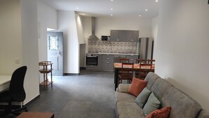 Ein modernes Wohnzimmer mit einer Couch, einem Esstisch und einer Küche im Hintergrund.