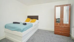 A bedroom with a bed, a wardrobe, and a radiator. - Charming Stoke-on-trent House Getaway (Stoke-on-Trent)