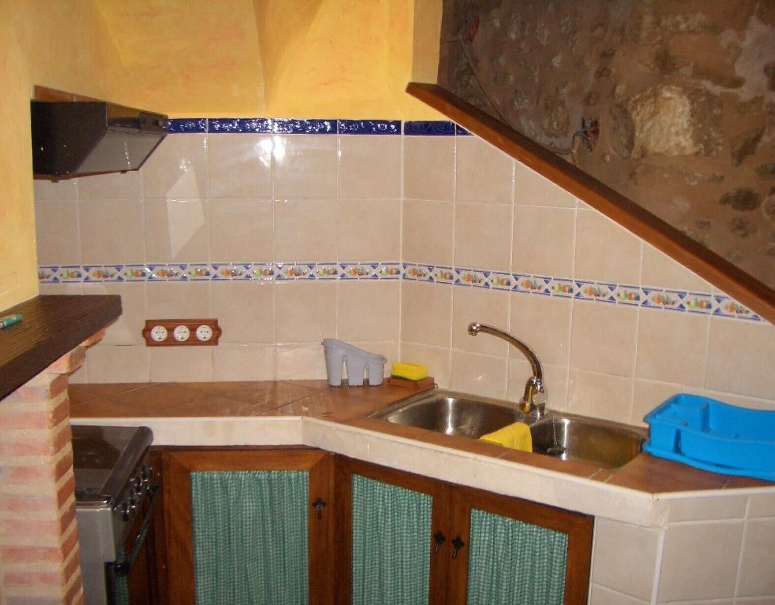 A kitchen with a stove, sink, and wooden cabinets.